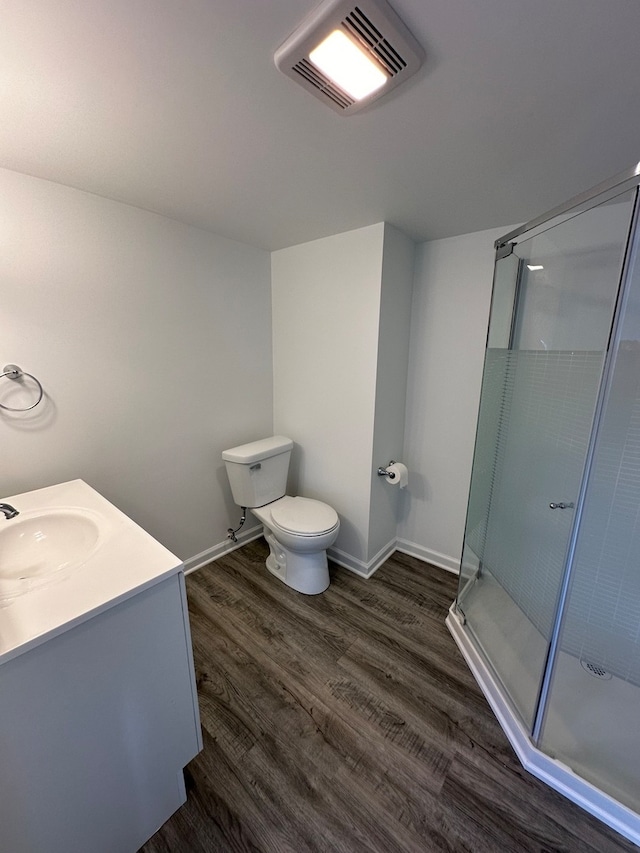 bathroom featuring hardwood / wood-style flooring, toilet, an enclosed shower, and vanity