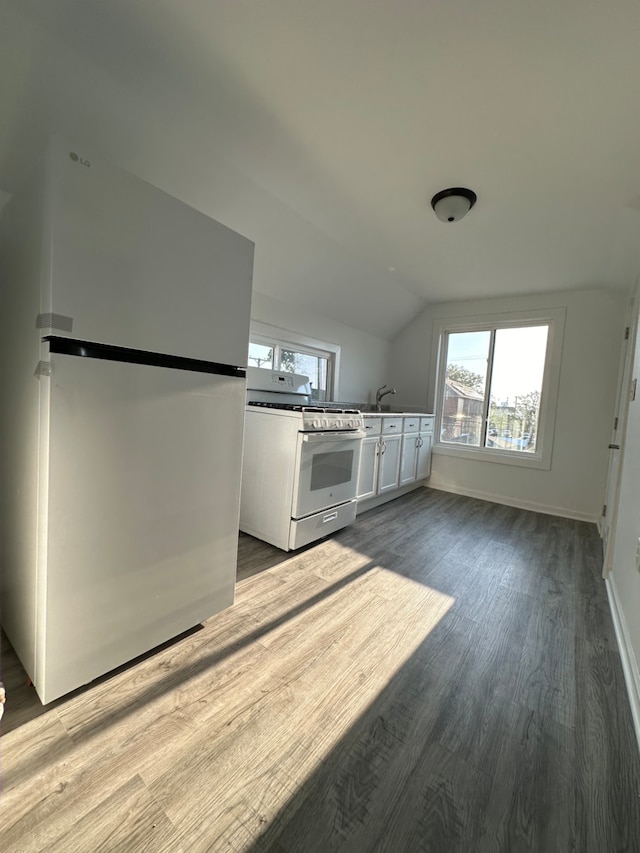 kitchen with sink, vaulted ceiling, white appliances, white cabinets, and light wood-type flooring