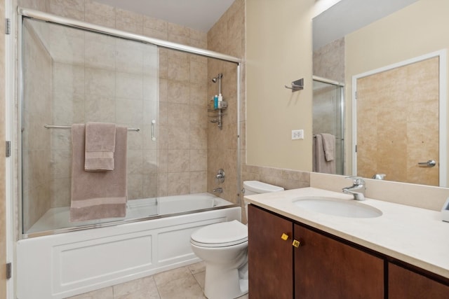 full bathroom with tile patterned floors, bath / shower combo with glass door, vanity, tile walls, and toilet