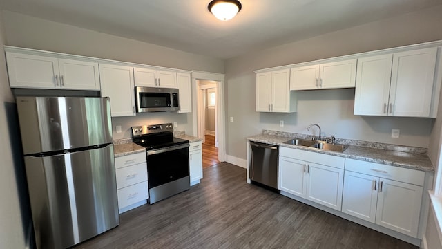 kitchen with appliances with stainless steel finishes, white cabinets, dark hardwood / wood-style flooring, and sink