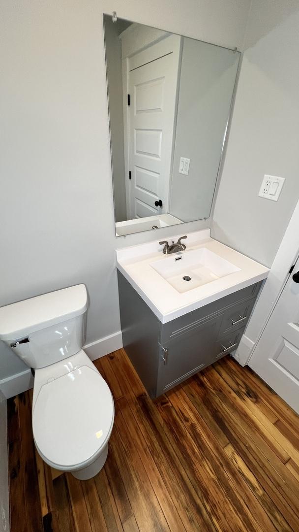 bathroom with wood-type flooring, toilet, and vanity