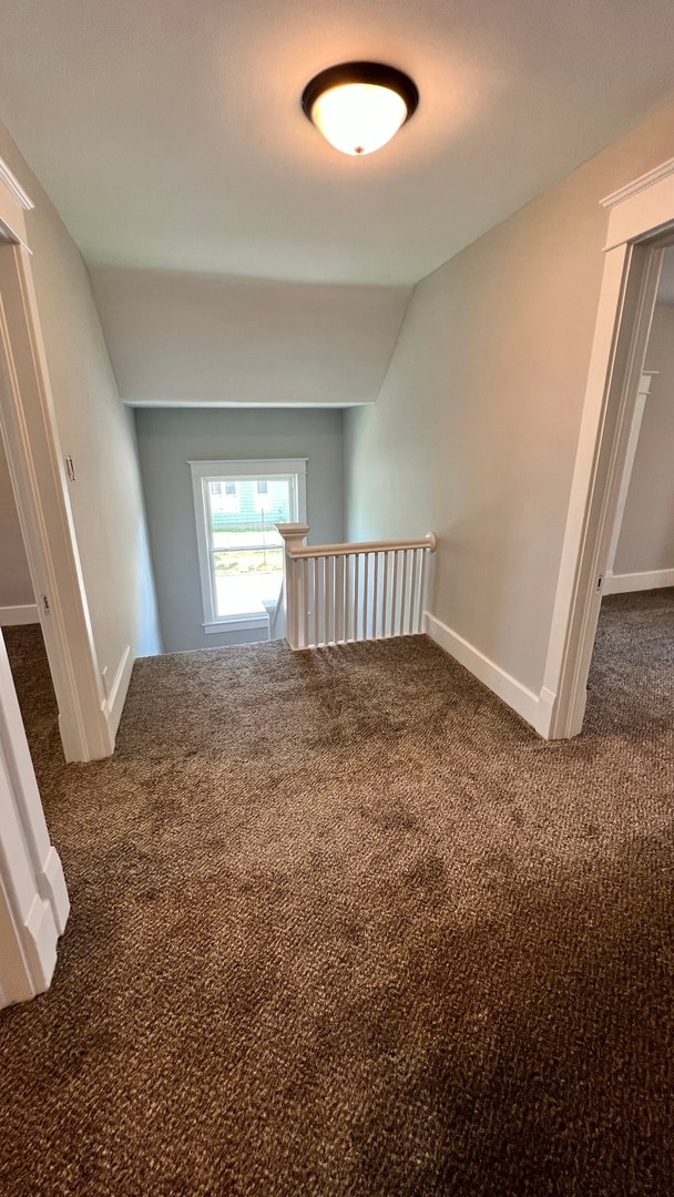 corridor featuring carpet and vaulted ceiling