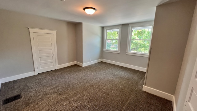 unfurnished bedroom featuring dark carpet and a closet