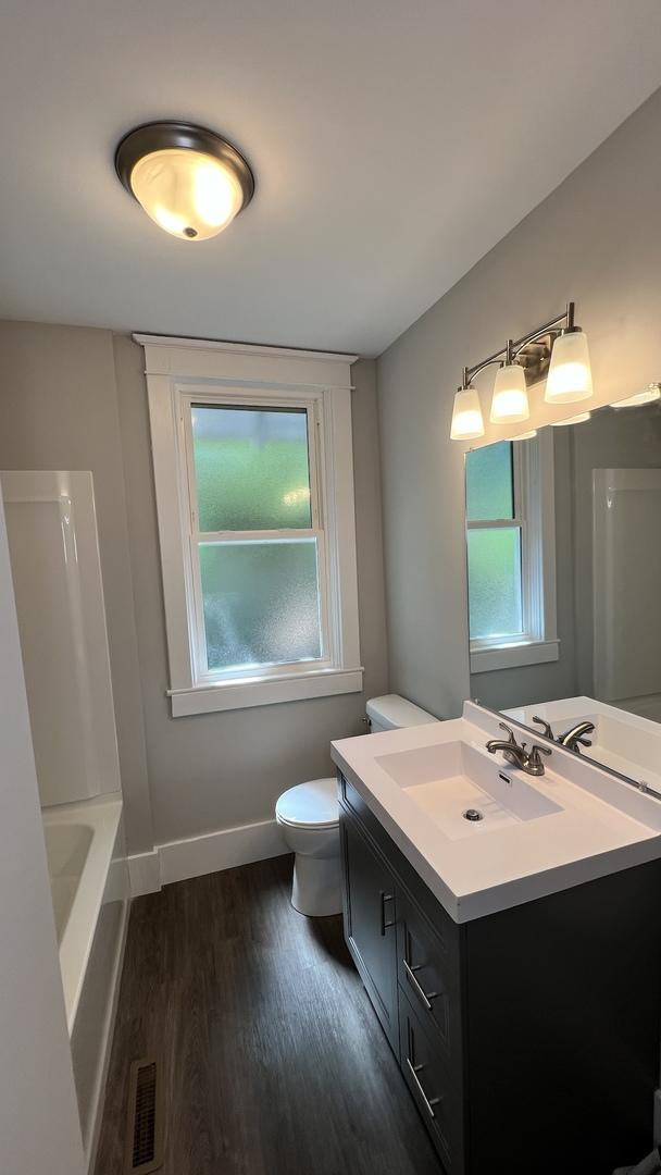 full bathroom with wood-type flooring, vanity, toilet, and tub / shower combination