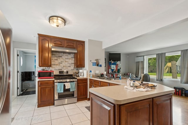 kitchen with appliances with stainless steel finishes, extractor fan, backsplash, sink, and kitchen peninsula