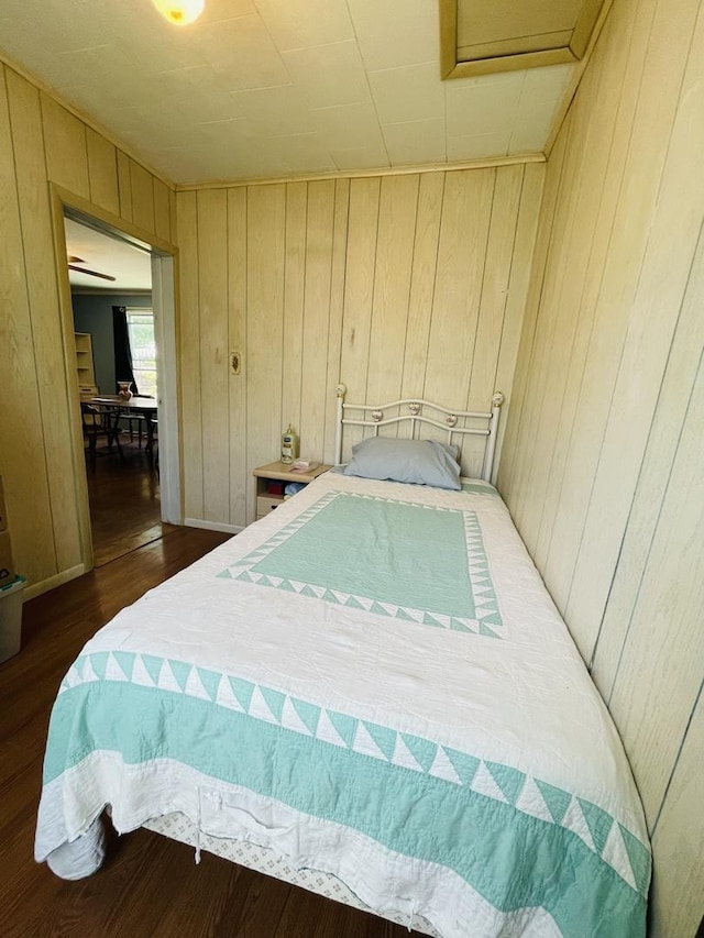 bedroom featuring dark hardwood / wood-style flooring and wooden walls