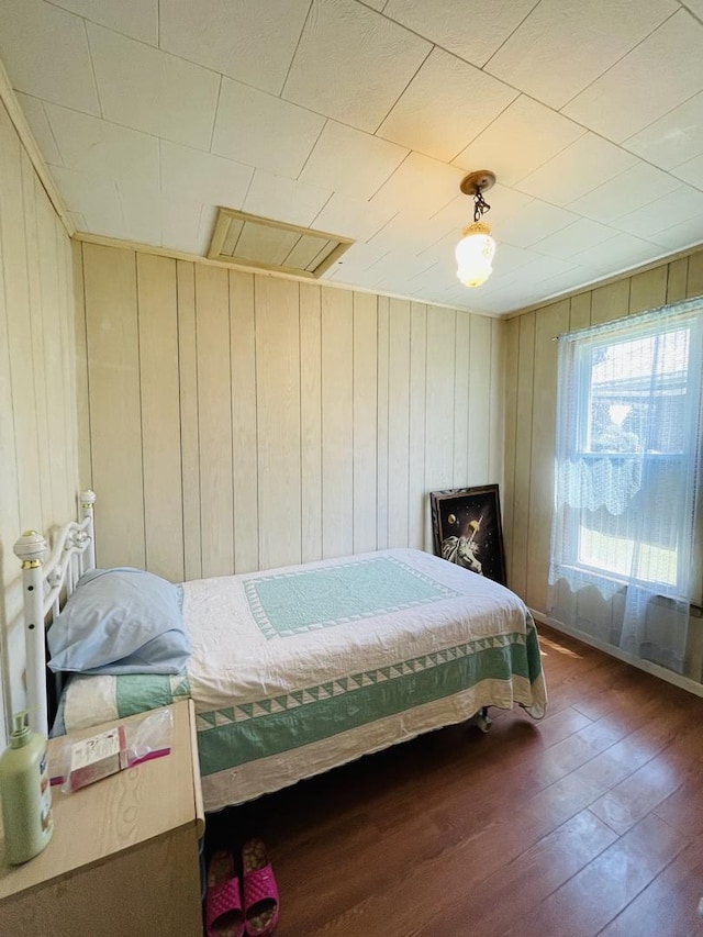 bedroom with dark hardwood / wood-style flooring and wood walls