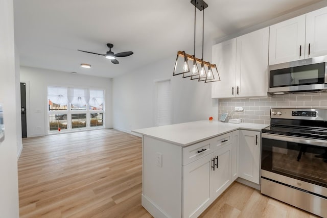 kitchen featuring stainless steel appliances, tasteful backsplash, kitchen peninsula, pendant lighting, and white cabinets