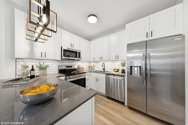 kitchen featuring backsplash, stainless steel appliances, sink, pendant lighting, and white cabinetry