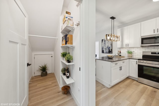 kitchen featuring appliances with stainless steel finishes, light wood-type flooring, pendant lighting, a notable chandelier, and white cabinets