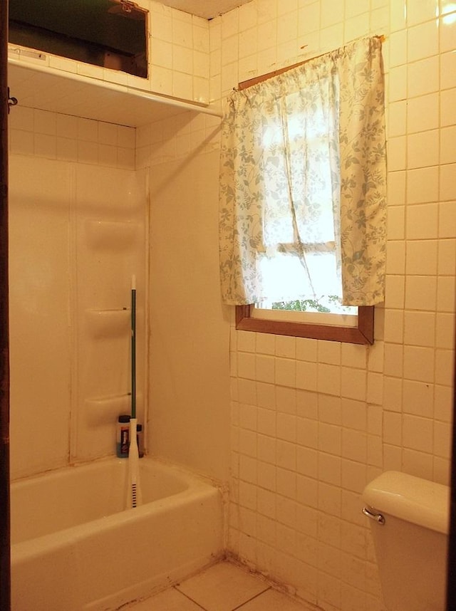 bathroom featuring shower / bathtub combination, tile patterned floors, toilet, and tile walls