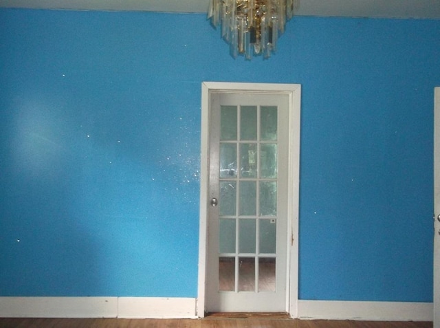 empty room featuring an inviting chandelier and wood-type flooring