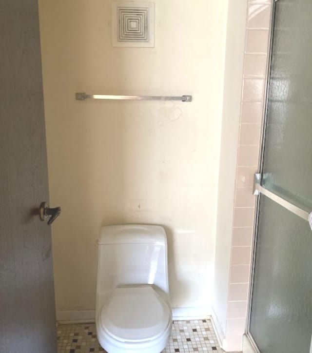 bathroom with tile patterned floors, toilet, and an enclosed shower