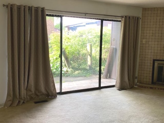 entryway featuring light carpet, plenty of natural light, and a fireplace