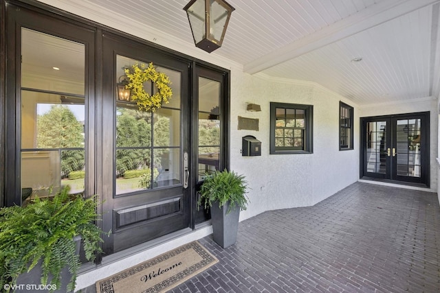 view of exterior entry featuring french doors and covered porch