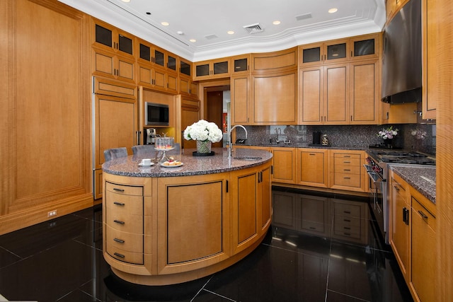 kitchen featuring exhaust hood, dark stone countertops, sink, a kitchen island with sink, and high end stainless steel range