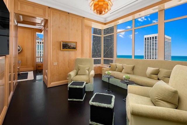 living room with crown molding, a water view, and wooden walls