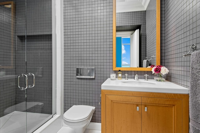 bathroom with toilet, vanity, tile walls, and an enclosed shower