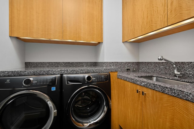 washroom with cabinets, washer and dryer, and sink