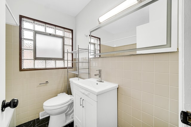 bathroom with vanity, toilet, and tile walls