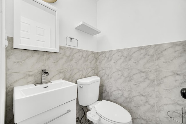 bathroom featuring vanity, toilet, and tile walls