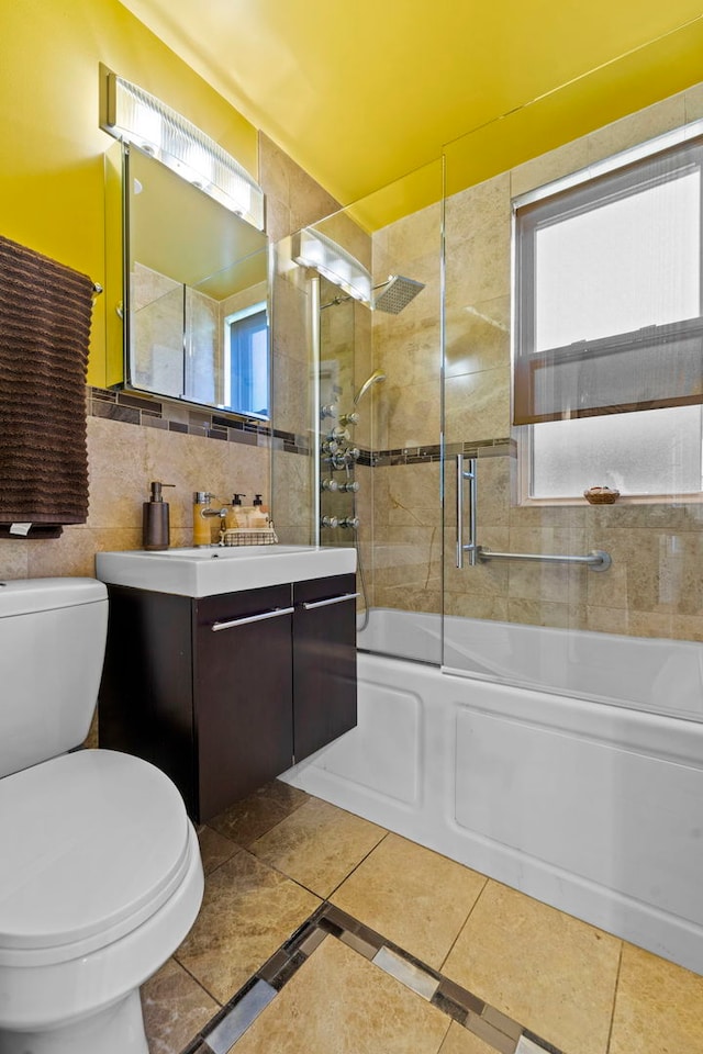 full bathroom with toilet, combined bath / shower with glass door, tile walls, vanity, and decorative backsplash