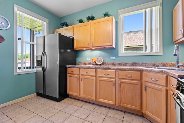 kitchen with stainless steel refrigerator with ice dispenser, stove, sink, and light tile patterned floors