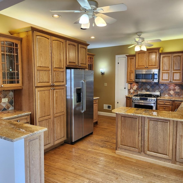 kitchen with stainless steel appliances, light stone counters, and tasteful backsplash