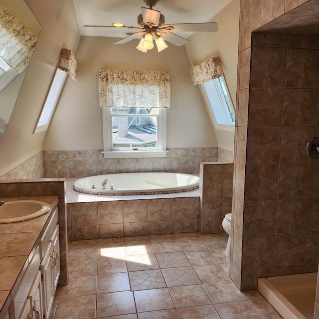 full bathroom with vanity, vaulted ceiling with skylight, ceiling fan, tile patterned flooring, and toilet