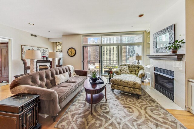 living room featuring light hardwood / wood-style flooring and a tiled fireplace