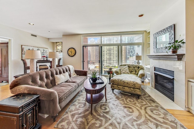 living room featuring a tiled fireplace and light hardwood / wood-style flooring