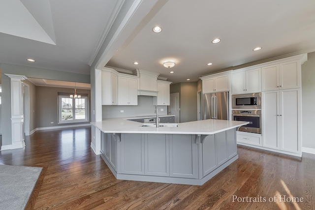 kitchen with a breakfast bar, dark hardwood / wood-style floors, white cabinetry, and stainless steel appliances