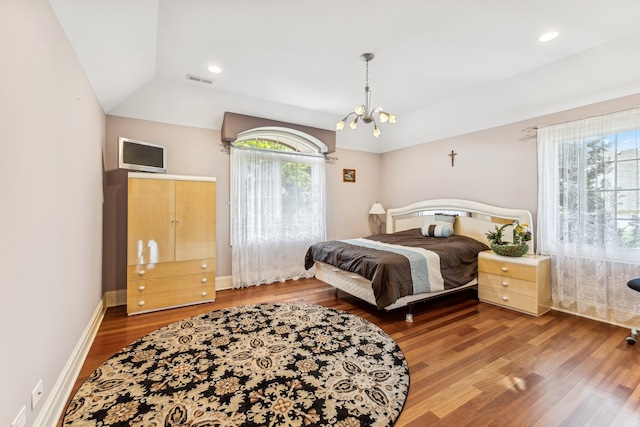 bedroom with a chandelier, vaulted ceiling, and hardwood / wood-style floors