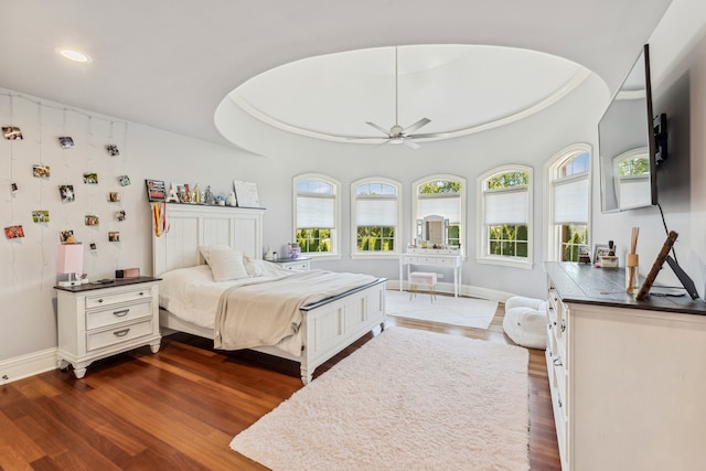 bedroom with ceiling fan, a raised ceiling, and dark wood-type flooring