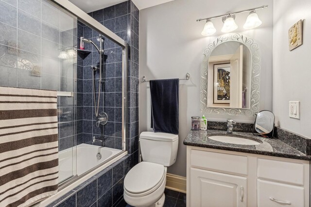 full bathroom featuring tile floors, shower / bath combination with glass door, toilet, and vanity