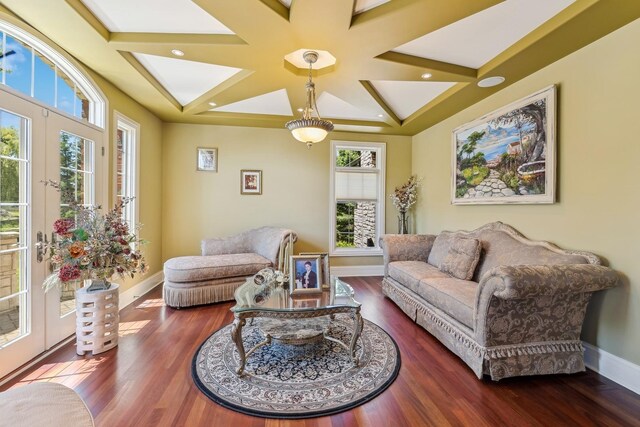 living room featuring a healthy amount of sunlight, dark wood-type flooring, and coffered ceiling