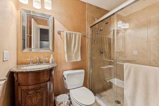 bathroom with a shower with shower door, vanity, and toilet