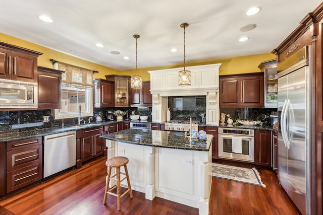 kitchen featuring a kitchen island, tasteful backsplash, built in appliances, dark wood-type flooring, and sink