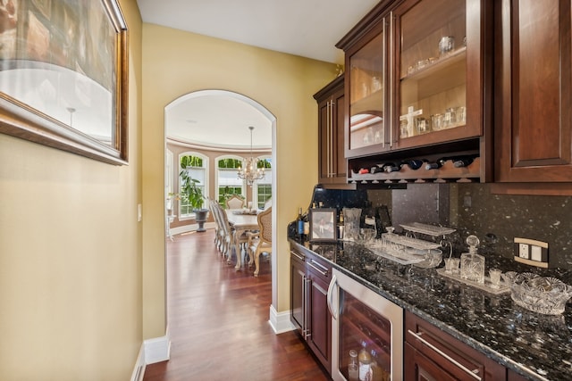 bar featuring beverage cooler, dark hardwood / wood-style floors, dark stone countertops, and backsplash