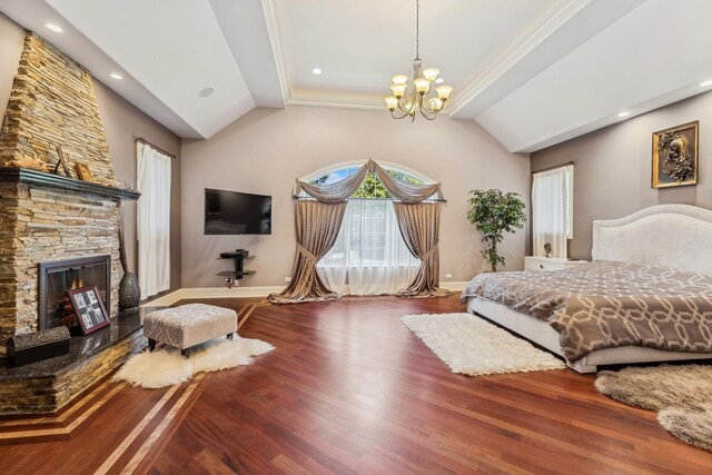 bedroom featuring crown molding, dark hardwood / wood-style floors, a stone fireplace, a notable chandelier, and vaulted ceiling