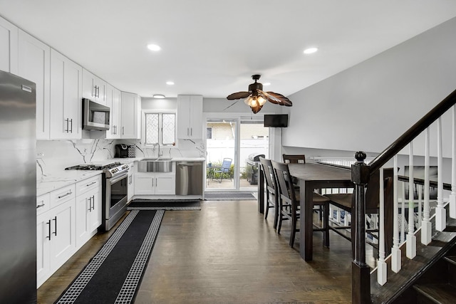 kitchen with ceiling fan, light stone counters, white cabinetry, and stainless steel appliances