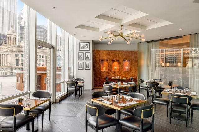 dining space featuring a notable chandelier, expansive windows, parquet floors, and coffered ceiling