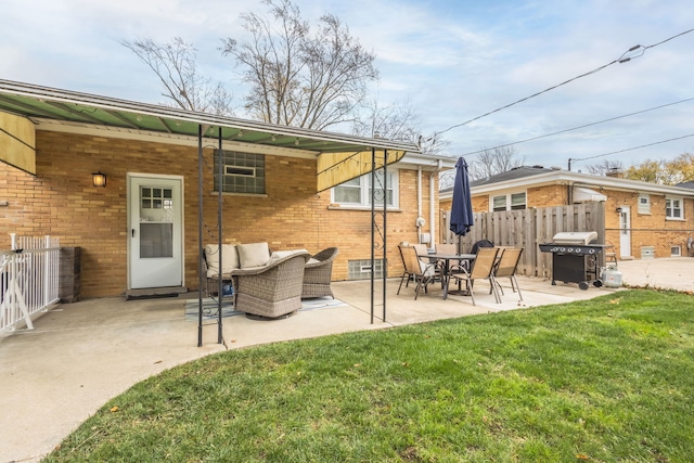back of house with a patio area, fence, brick siding, an outdoor living space, and a lawn