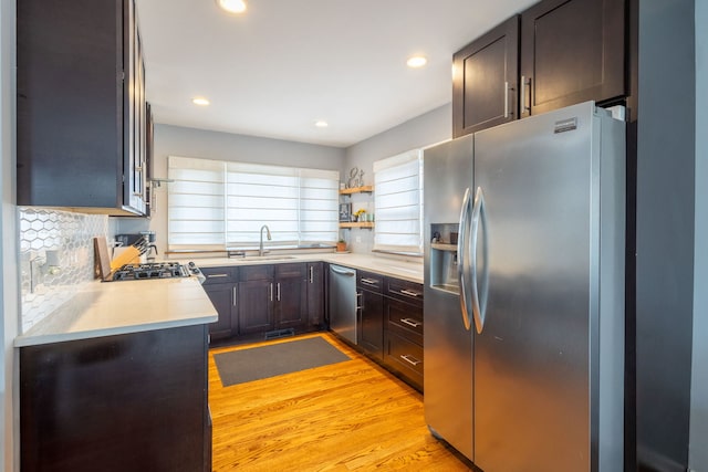 kitchen featuring a sink, stainless steel appliances, recessed lighting, light wood finished floors, and light countertops