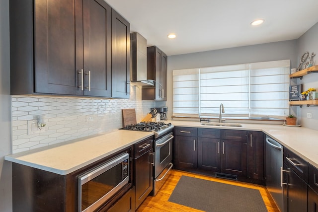 kitchen with a sink, wall chimney range hood, open shelves, light countertops, and appliances with stainless steel finishes