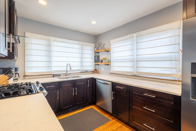 kitchen with light countertops, a sink, dark brown cabinetry, light wood-type flooring, and dishwasher
