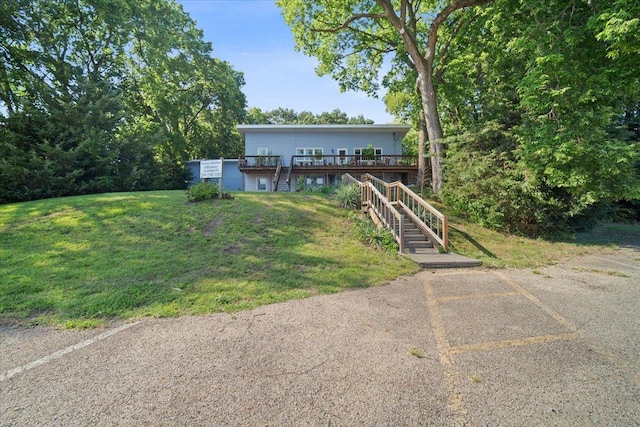 view of front facade featuring stairway, a wooden deck, and a front yard