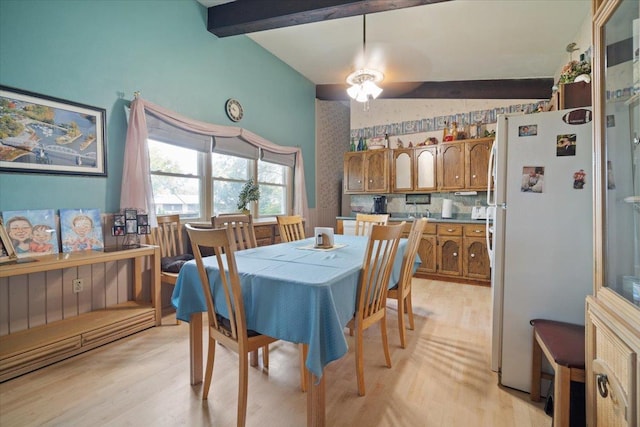 dining space with light wood finished floors and vaulted ceiling with beams