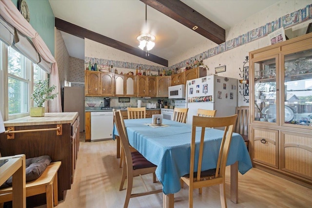 dining room featuring lofted ceiling with beams, light wood-type flooring, ceiling fan, and wallpapered walls