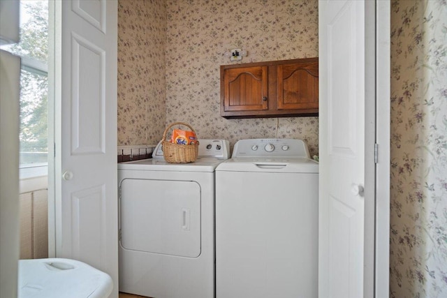 washroom with wallpapered walls, cabinet space, and washer and clothes dryer